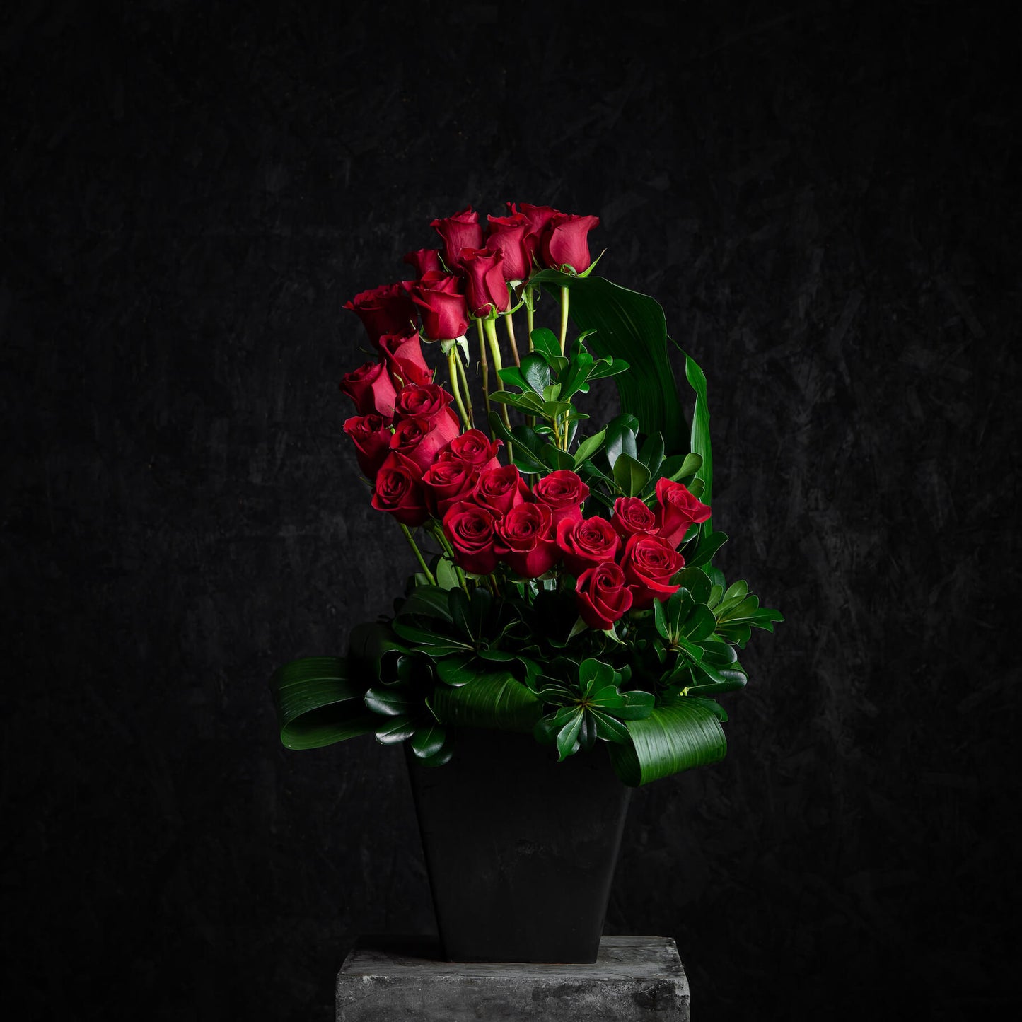 Bouquet of red roses in a black pot on a dark background