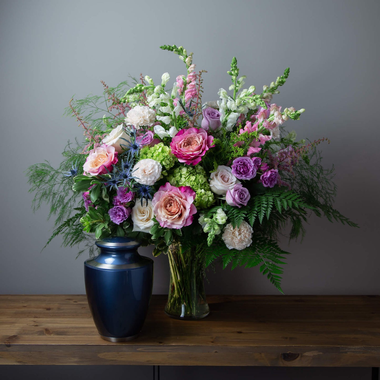 Bouquet of flowers in a clear vase on a wooden table with a gray background