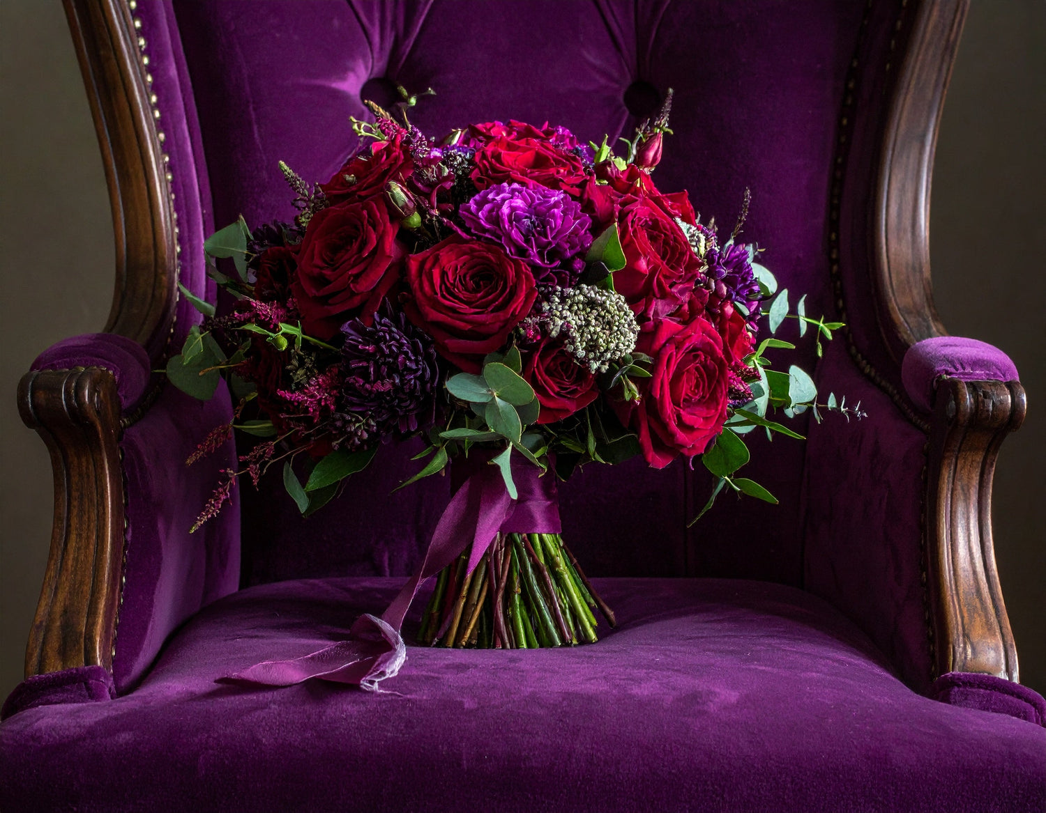 Colorful bridal bouquet sitting in purple velvet armchair