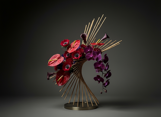 Decorative floral arrangement with red and purple flowers on a gold stand against a dark background