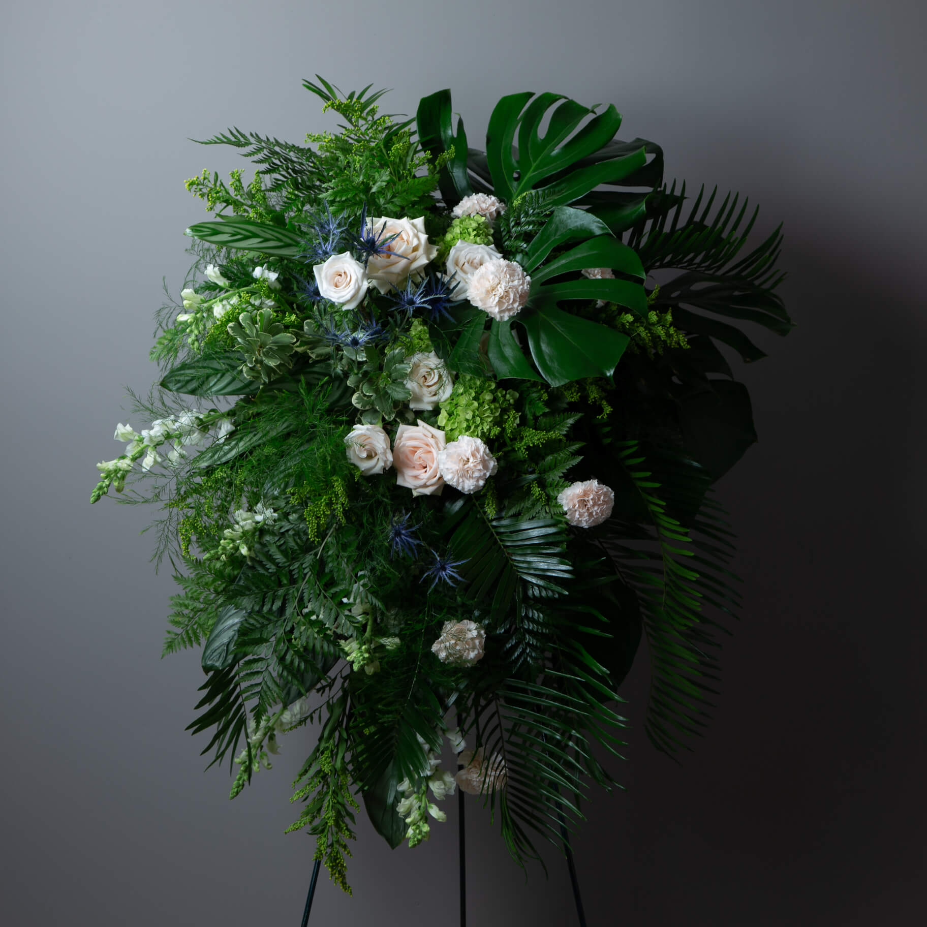 Floral arrangement with greenery and white flowers on a dark background
